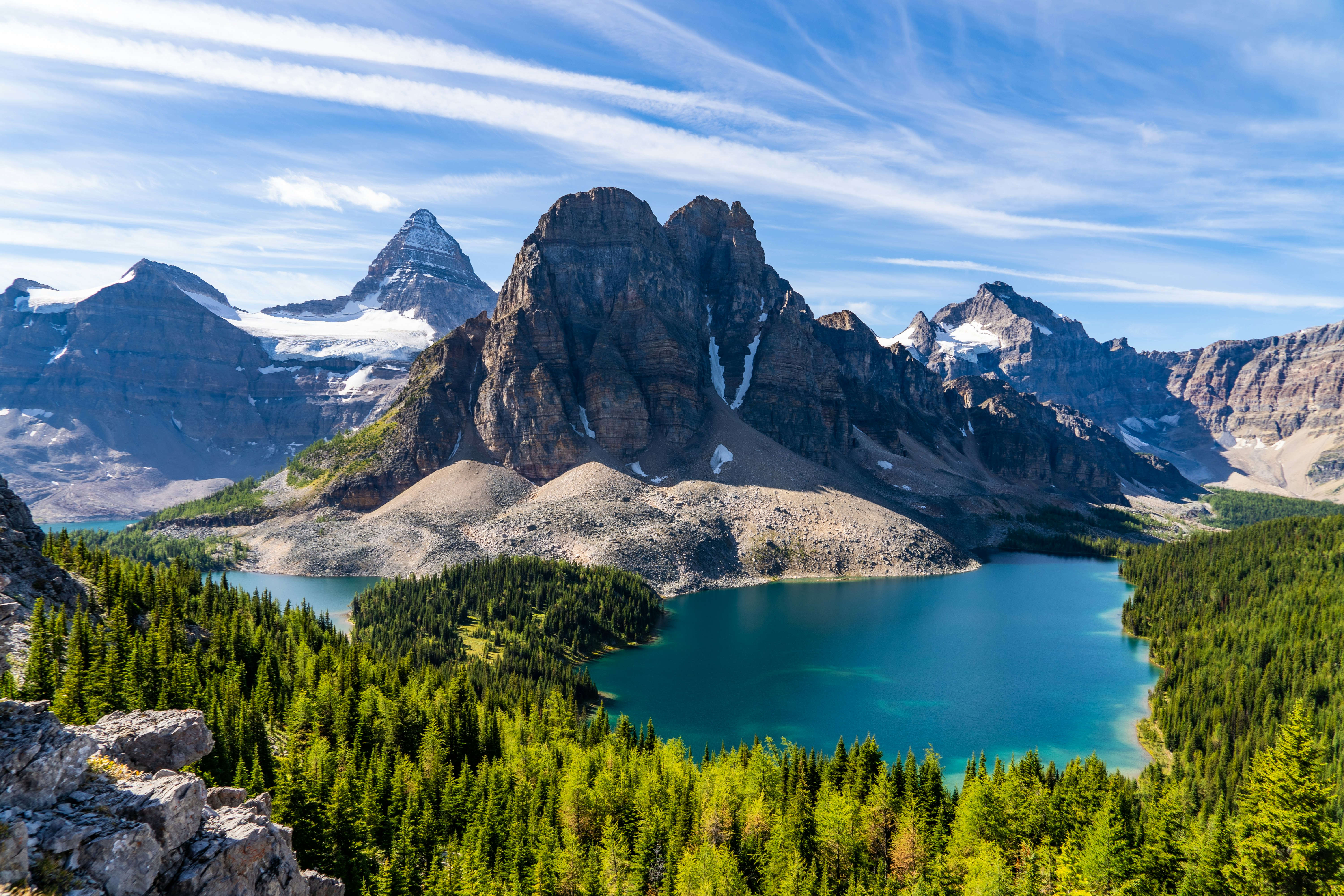 green trees near lake and mountain under blue sky during daytime